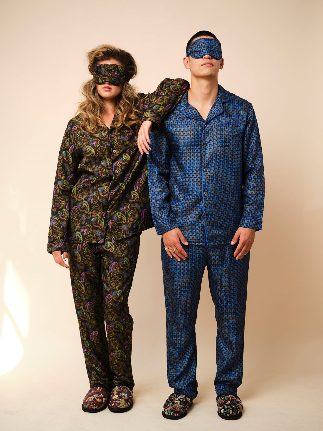 Two models in Gresham Blake silk pyjamas, eye masks and tapestry slippers