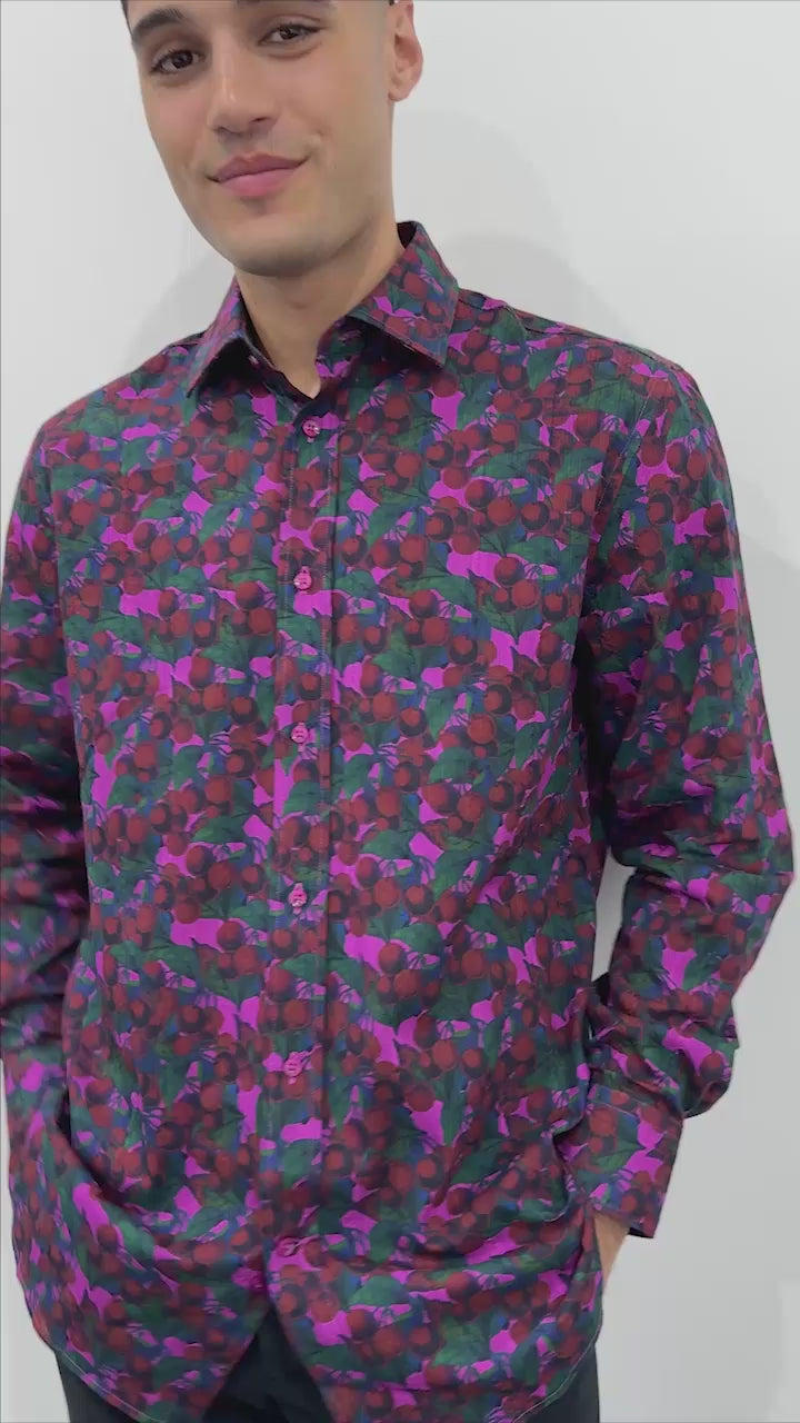 model wearing a printed shirt with design of cherries in pink, red and purple